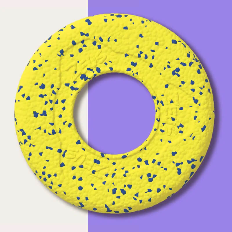 Zeus Nitro Flying Disc, yellow with blue specks, on split cream and purple background.