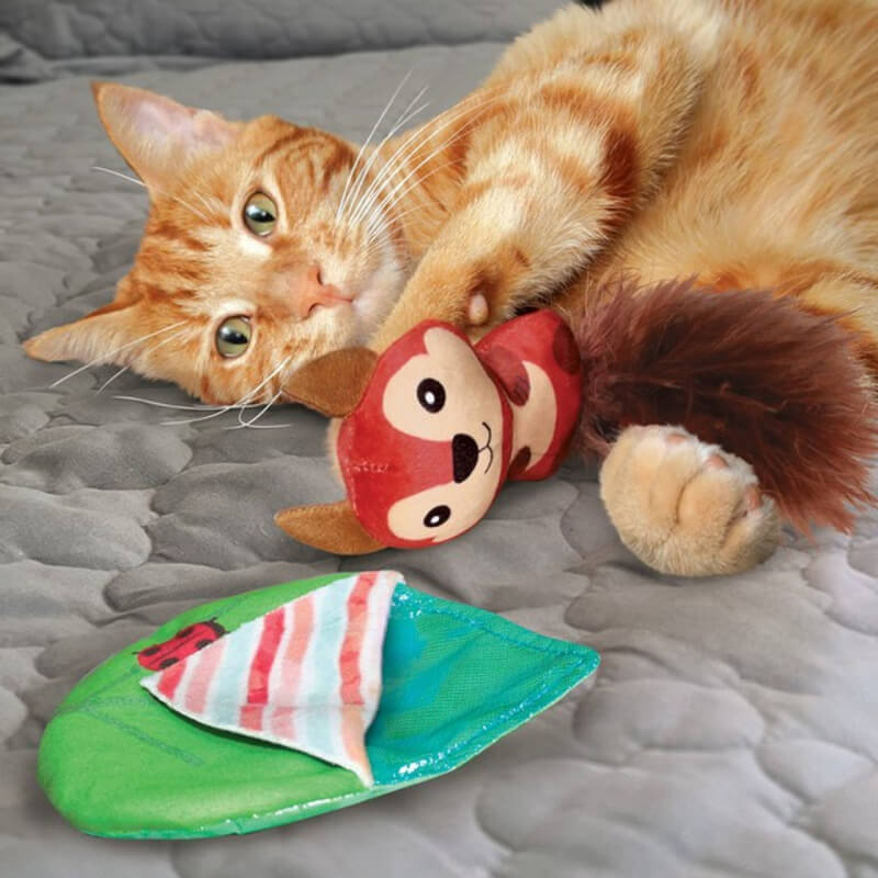 Orange cat on gray blanket shows hunting instincts with the Kong Pull-A-Partz Tuck cat toy.