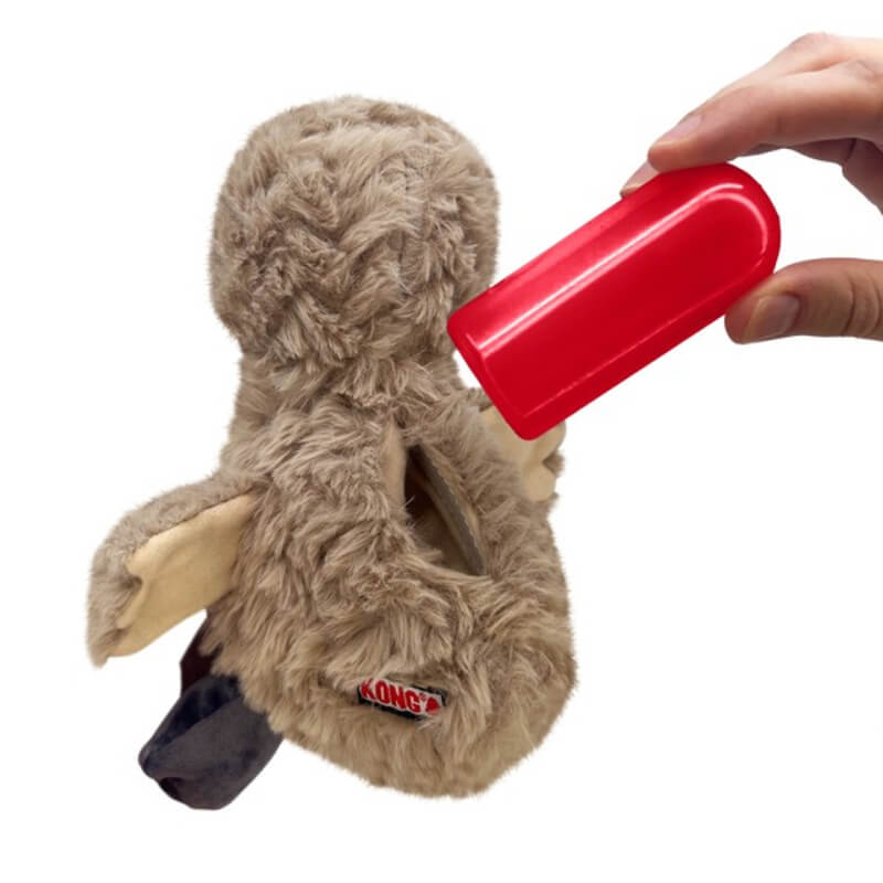 A hand inserts a red squeaker into the KONG Comfort Tykes Goat Small by Kong.