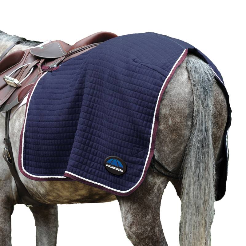 A grey horse with a navy saddle pad, brown saddle, and a Weatherbeeta Thermocell fleece sheet.