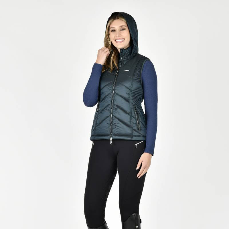 Woman smiles in a Weatherbeeta Presley Puffer Vest Pine over a blue top and black pants.