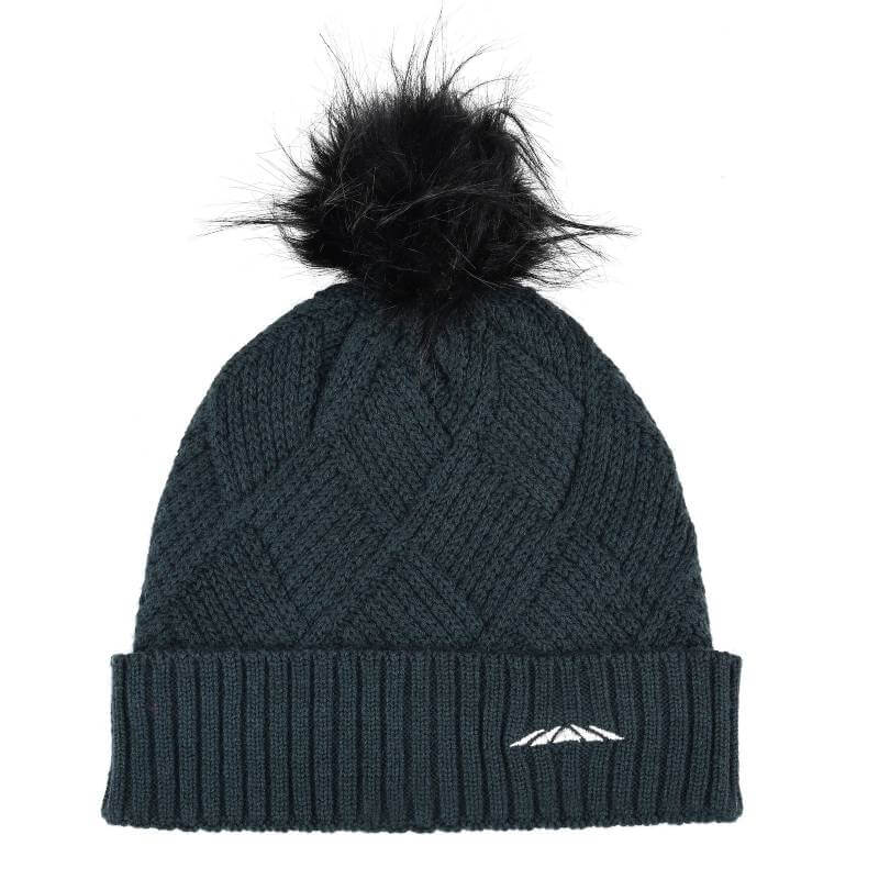 Woman outdoors in a Weatherbeeta Beanie Pine, dark jacket, grassy field in the background.