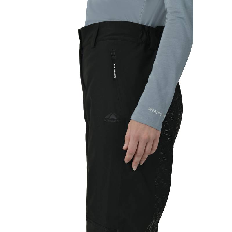Person in a light grey top and black/white Weatherbeeta Rayne Waterproof Overtrousers II, side view.