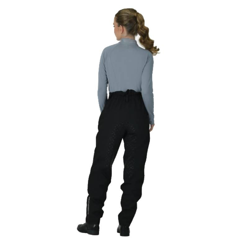 Woman in a gray top and Weatherbeeta Rayne Waterproof Overtrousers II stands facing away.