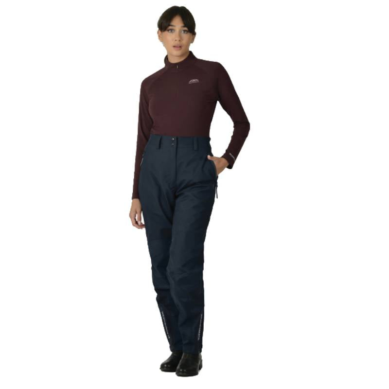 Woman in a maroon top and Weatherbeeta Rayne Waterproof Overtrousers II stands facing forward.