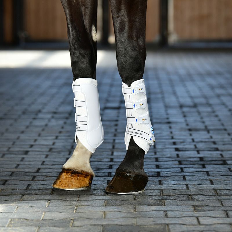 Horse legs with Weatherbeeta Tough-Tec Hard Shell Dressage Boots White on a tiled floor.