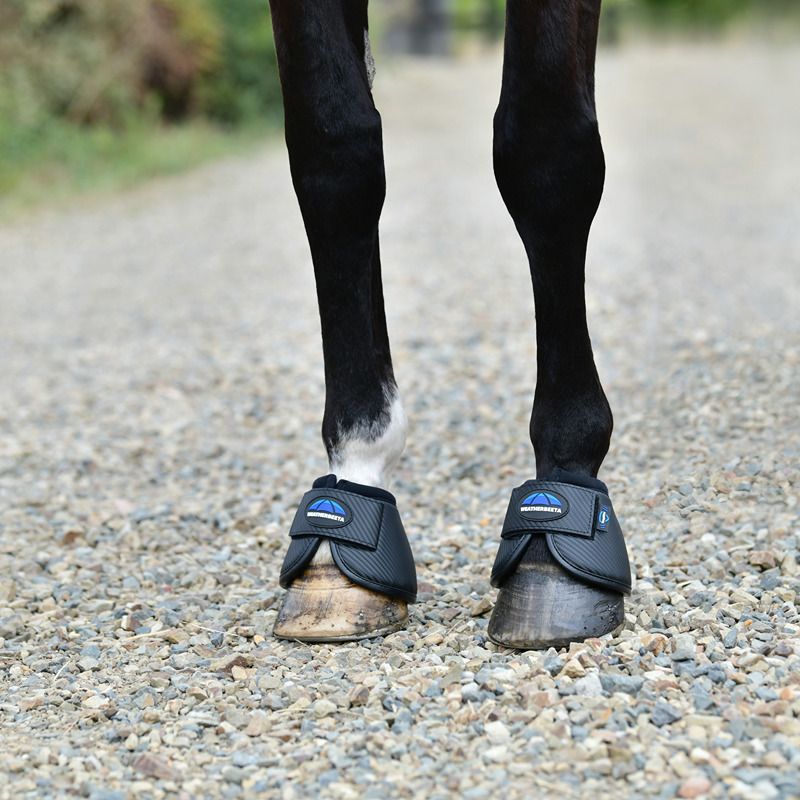 Close-up of horse legs in Weatherbeeta Tough-Tec Anatomical Bell Boots Black on gravel.