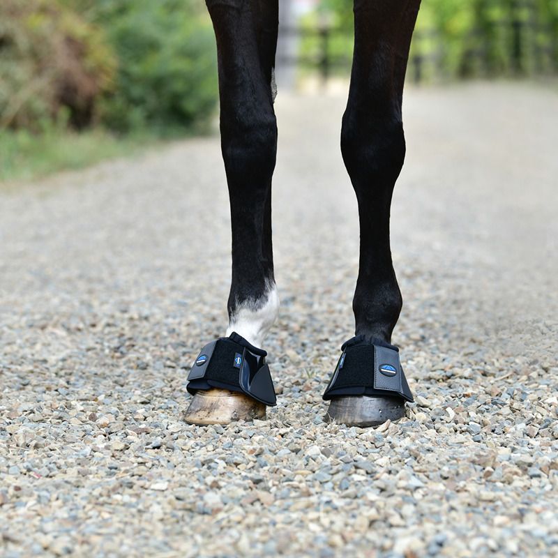 A horse on gravel wears Weatherbeeta Tough-Tec Impact Bell Boots Black for hoof protection.