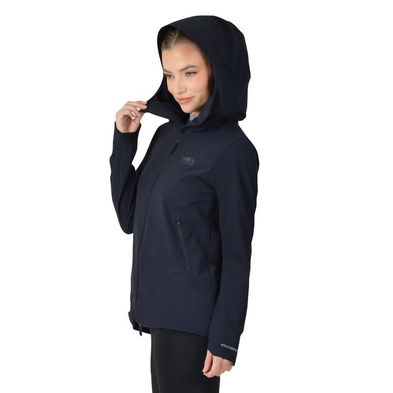 Woman in a Weatherbeeta navy stretch riding jacket stands sideways, looking slightly downward.