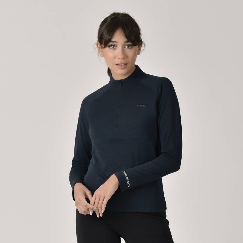 Woman wears a Weatherbeeta Bamboo LS Base Layer Navy and black pants on light background.