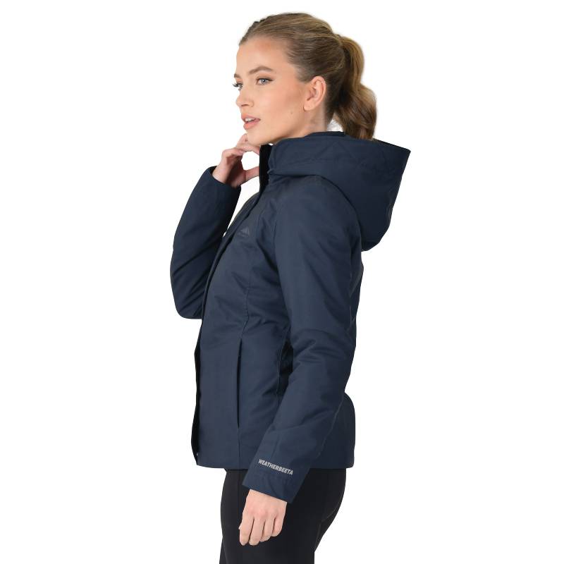 Woman in a Weatherbeeta Protect Jacket With High Neck Navy, standing sideways holding collar.