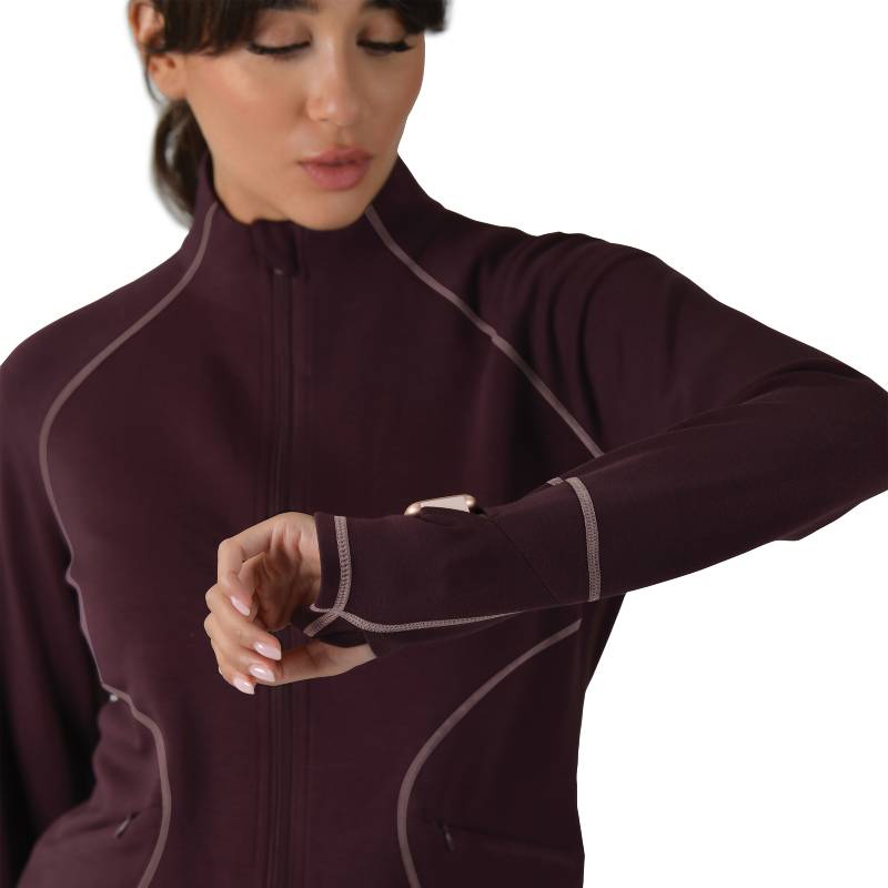 Woman in a Weatherbeeta Copper Performance Jacket Mulberry checks her smartwatch.