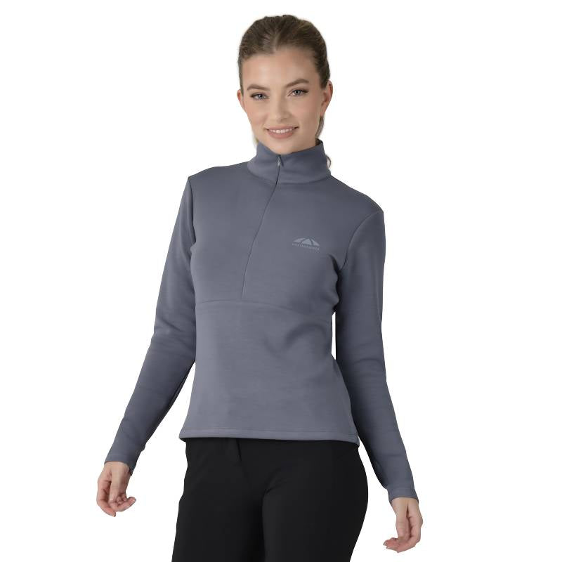 Woman in a slate blue Weatherbeeta Copper 1/2 zip mid-layer, smiling with hands clasped.