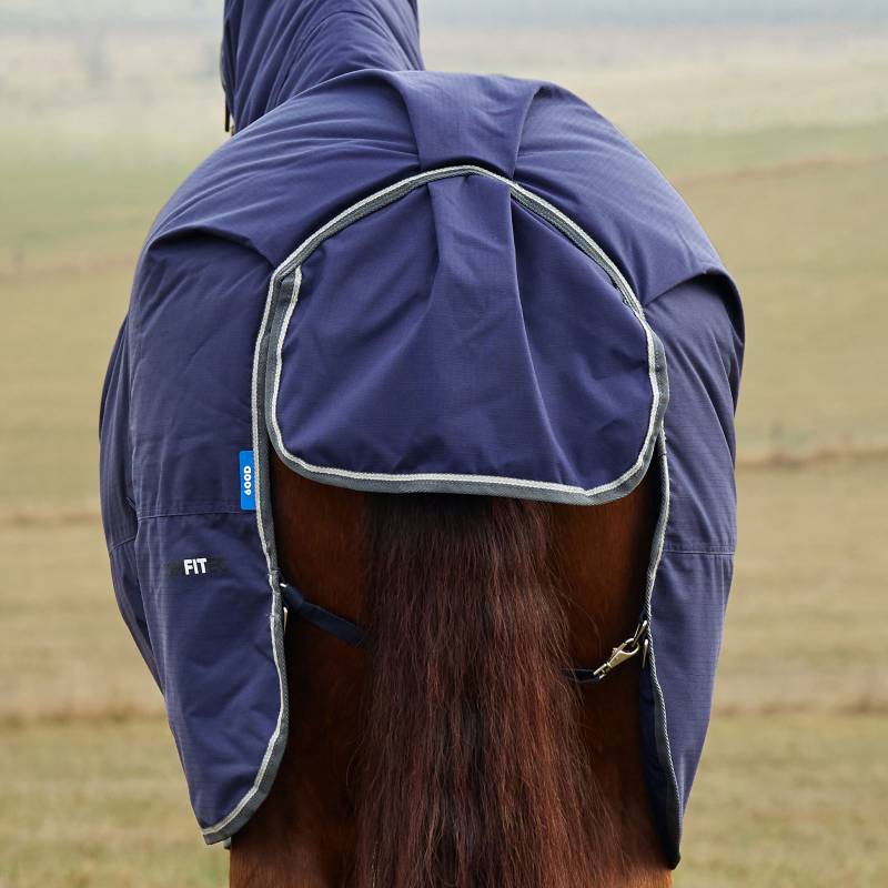 A horse in a Weatherbeeta Comfitec Tyro Combo Neck Turnout Rug stands in an open field.
