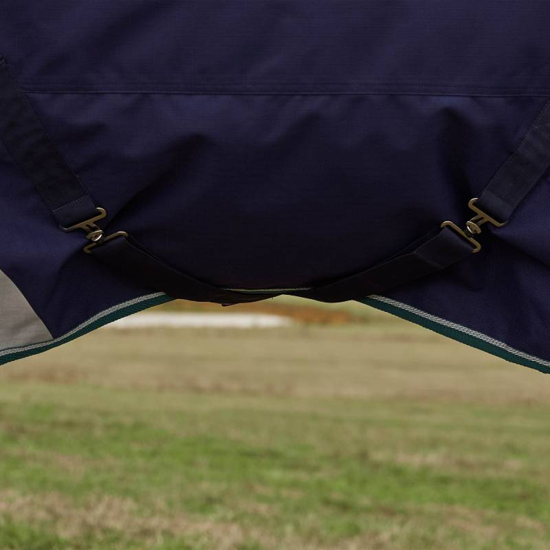 Weatherbeeta straps on navy/forest green Comfitec Plus Dynamic turnout rug in grassy field.