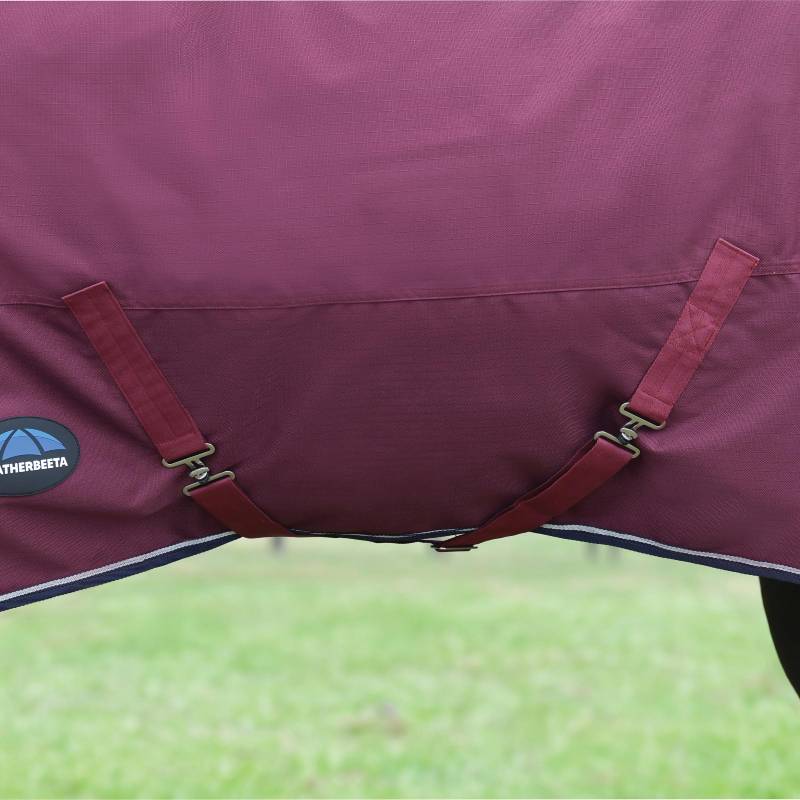 Close-up of Weatherbeeta Comfitec Essential Turnout Rug 50g, Burgundy/Navy, on grass.