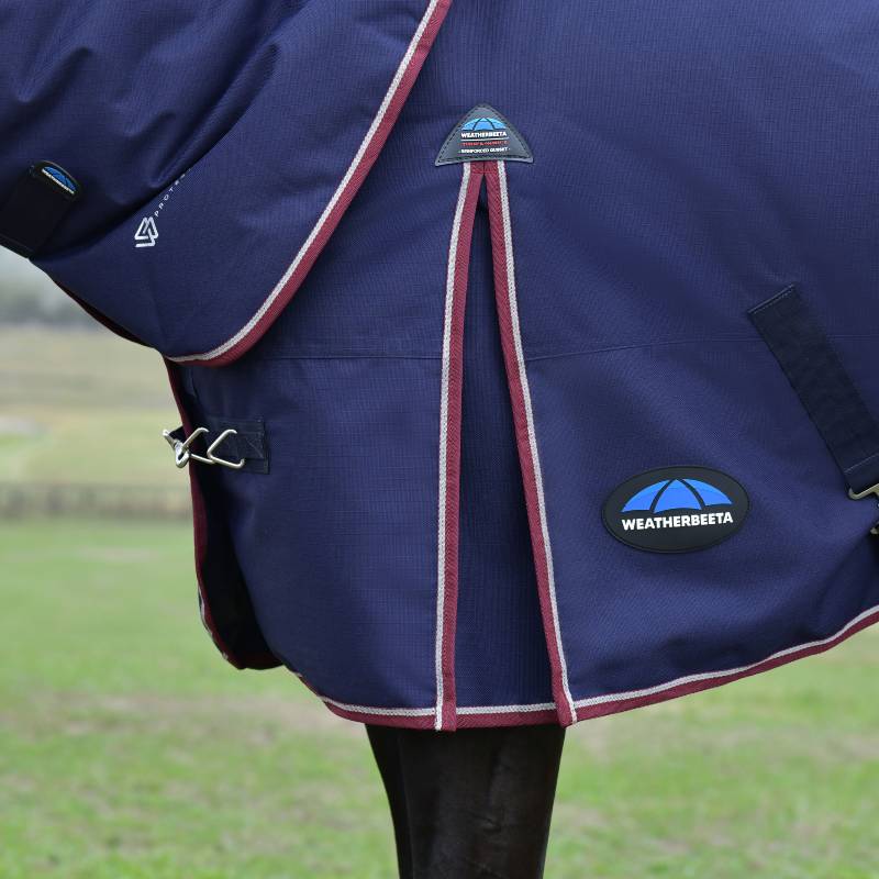 Horse wearing a Weatherbeeta Comfitec Essential Turnout Rug in navy/burgundy on grass.