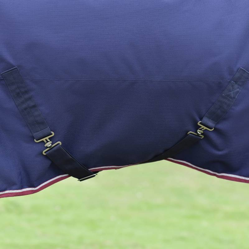 Close-up of Weatherbeeta Comfitec Essential 220g Turnout Rug in navy/burgundy on green grass.