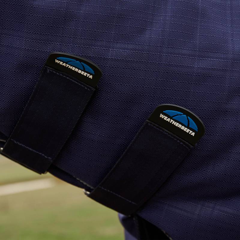 Close-up of two Weatherbeeta Comfitec Prelim Combo Neck Turnout Rug straps on navy plaid.