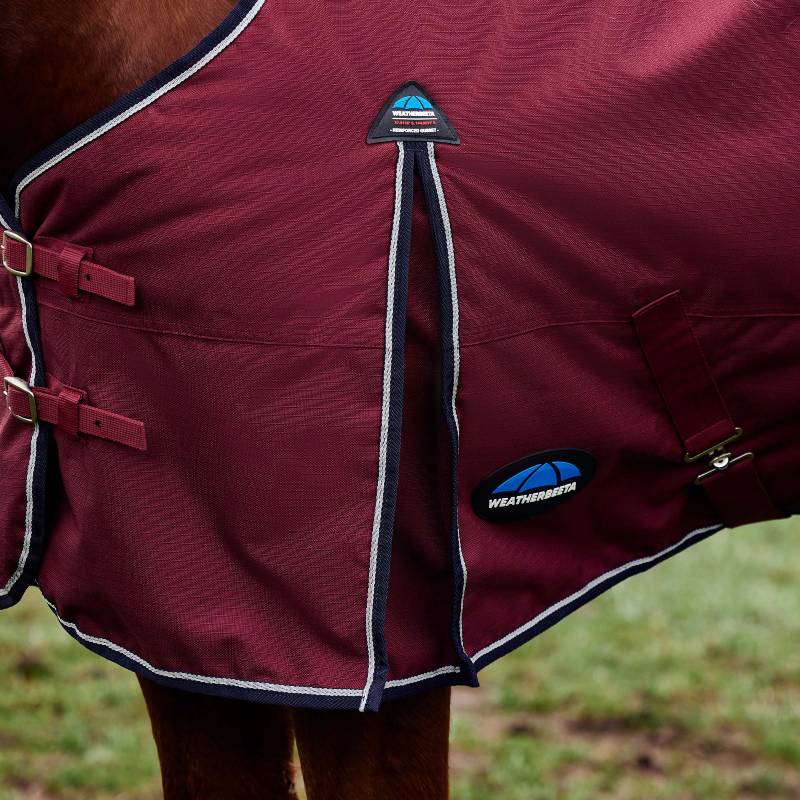 A horse in a burgundy Weatherbeeta Comfitec 220g rug stands on grass.