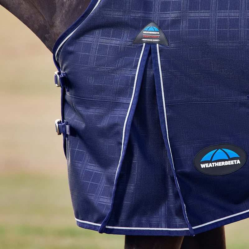 Close-up of a horse in a navy Weatherbeeta Comfitec Prelim turnout rug, logo and buckles visible.