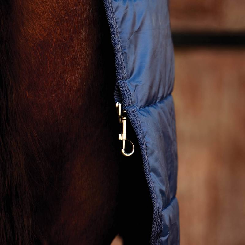 Brown horse in a navy Weatherbeeta Comfitec Thermi-Heat Liner 100g by wooden stable doors.