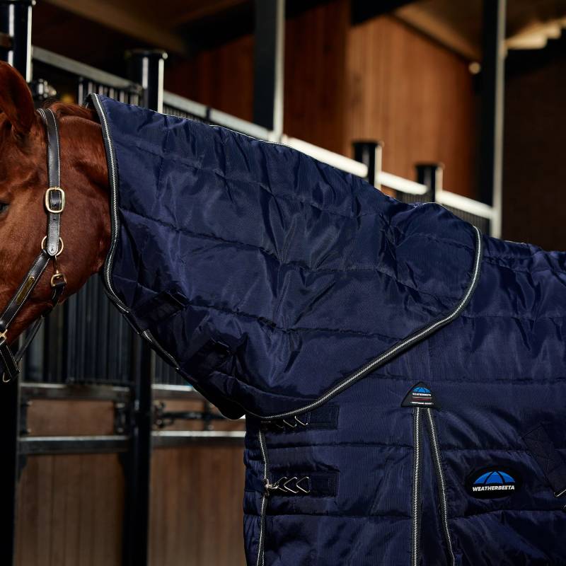 A horse wears a Weatherbeeta Comfitec PP Channel Quilt Stable Rug 220g Navy/Charcoal in a stable.