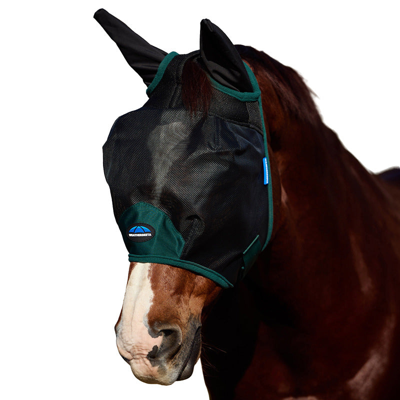A horse wears a Weatherbeeta Comfitec mesh fly mask with ears, black/forest green, outdoors.