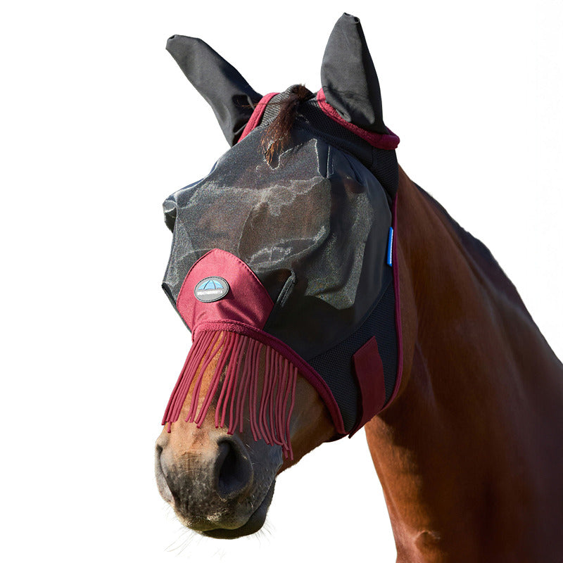 A horse wearing a Weatherbeeta Comfitec Fine Mesh Fly Mask with ears and nose tassels.