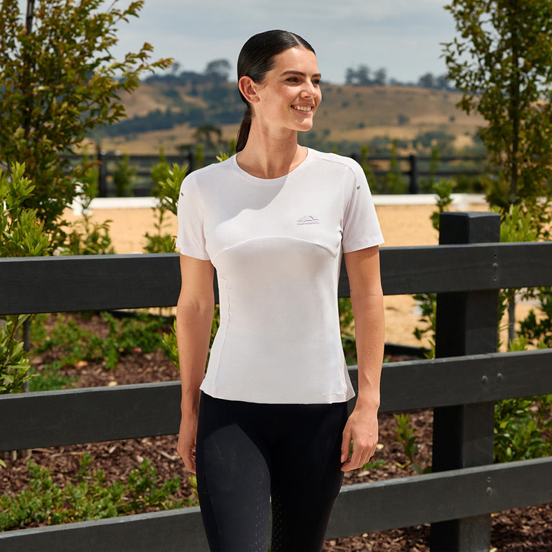 Woman in Weatherbeeta 37.5 Lite Perf SS Top Lavender Mist Marle smiles outdoors by a fence.