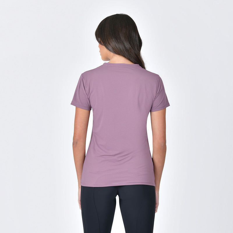 Woman in a Weatherbeeta mauve tee and black leggings stands with one hand on her hip.