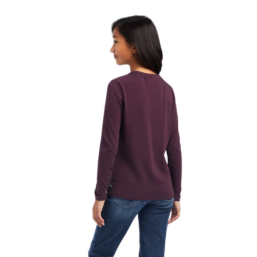 Girl in Ariat Youth Dream Long Sleeve T Shirt Mulberry and jeans, standing and facing away.