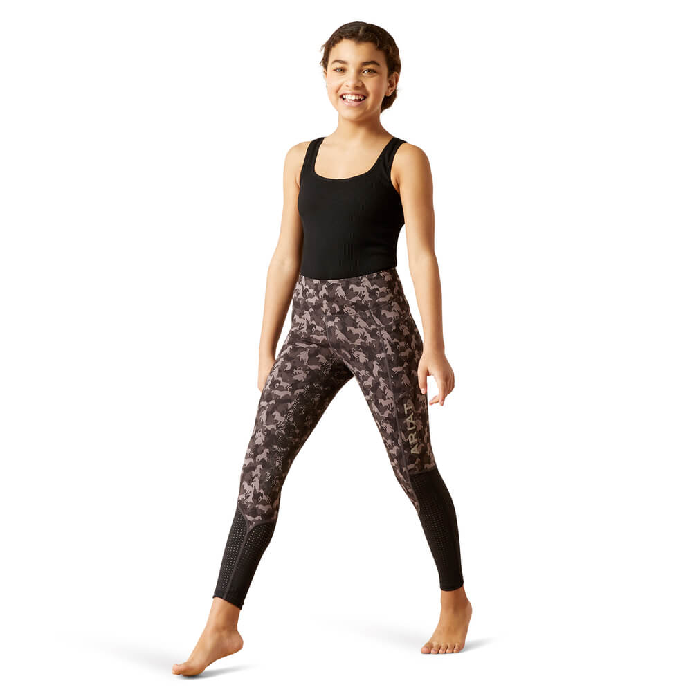 Barefoot girl in black tank and Ariat Youth Eos Full Seat Tight Periscope Camo poses playfully.