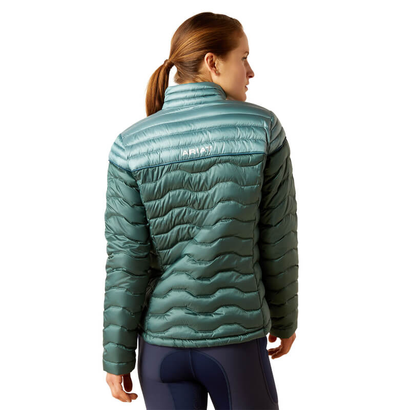 Woman in an Ariat Ideal Down Jacket Iridescent Arctic, navy leggings, looking left.