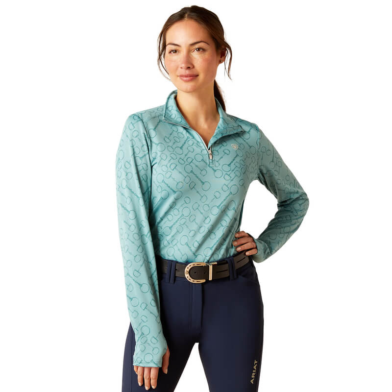 Woman in a light blue Ariat Womens Prophecy 1/4 Zip Arctic and navy pants with a belt.