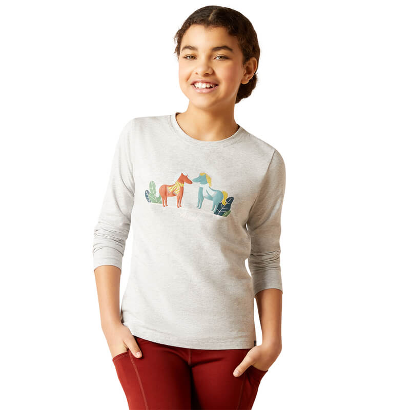 Smiling girl in Ariat Youth Winter Fashions Long Sleeve Top, hands in pockets.