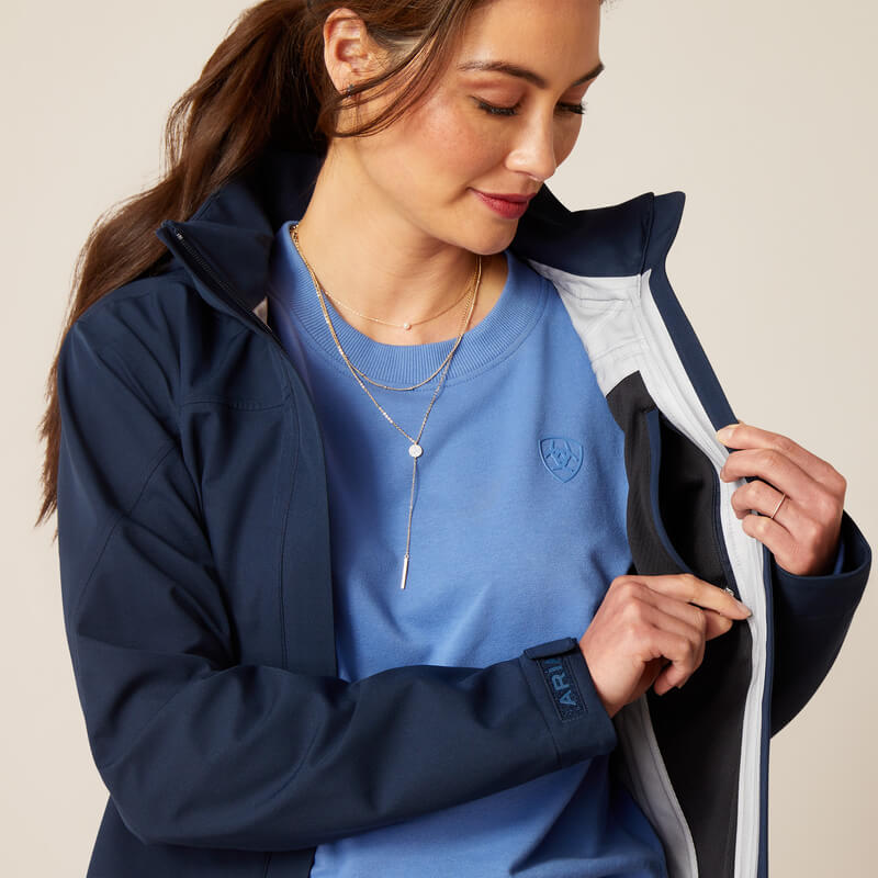 Woman in Ariat Womens Coastal Long H2O Parka Navy opens it to show the inner lining.