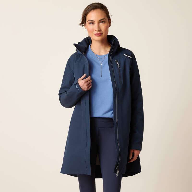 Woman in Ariat Womens Coastal Long H2O Parka Navy, blue shirt, and leggings.