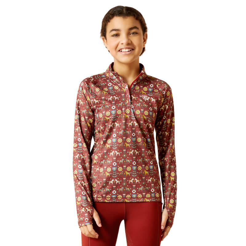 Smiling girl in maroon Ariat Youth Lowell 2.0 1/4 Zip Baselayer and red pants, facing forward.