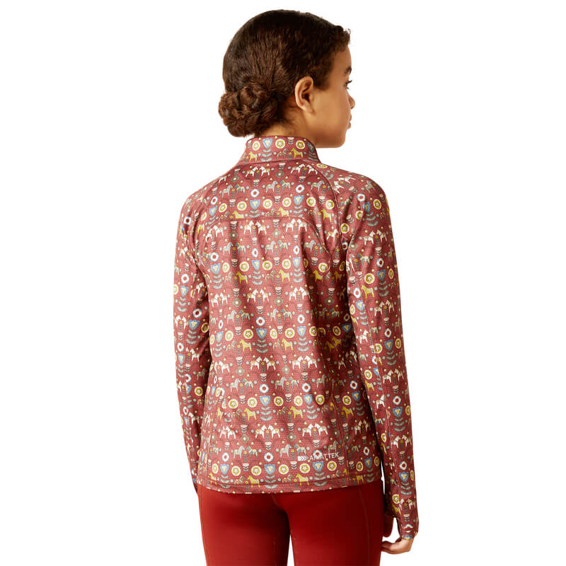 A child in an Ariat Youth Lowell 2.0 1/4 Zip Baselayer Dala Horse shirt and red pants.