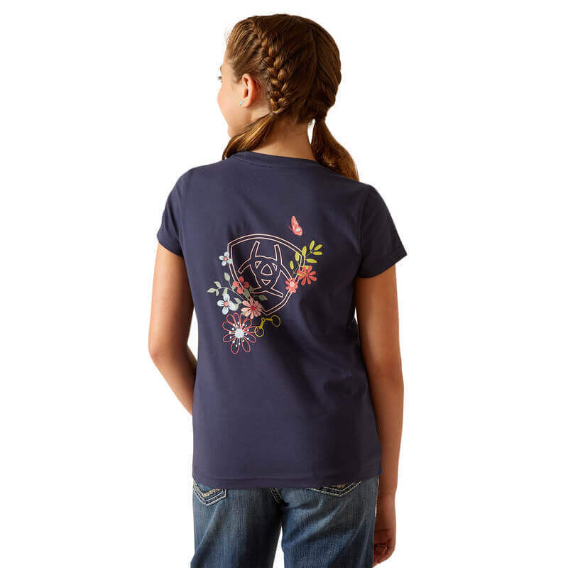 Girl with braids wears Ariat Youth Pretty Shield SS Top Navy Eclipse with floral logo dog on back.