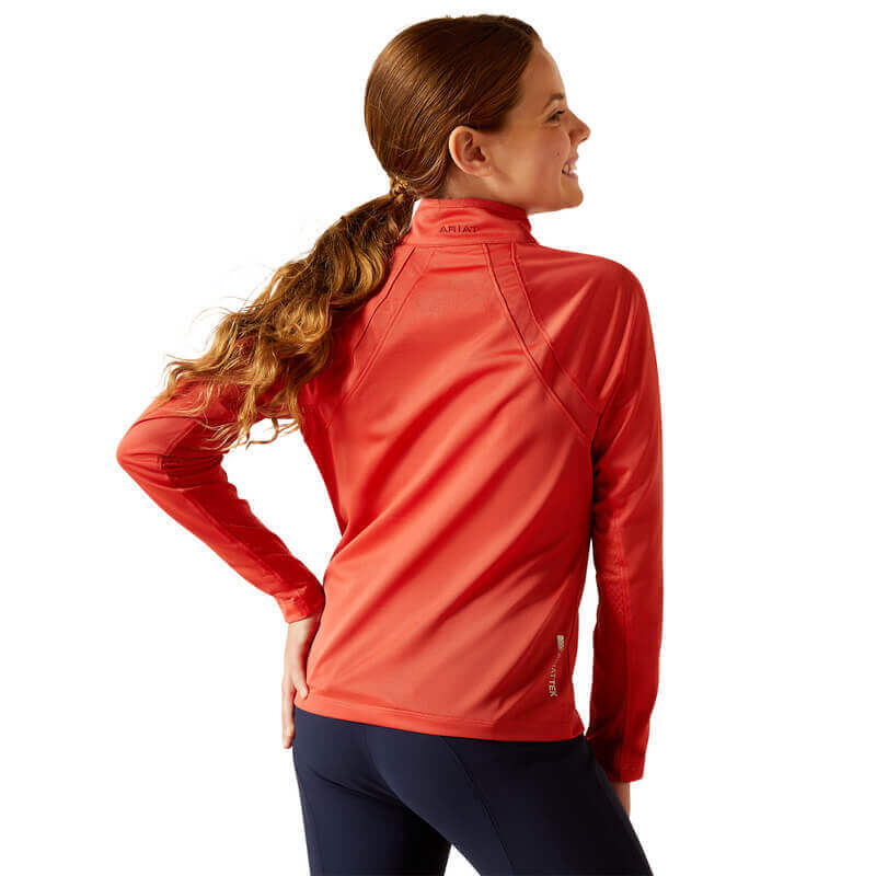 Girl in Ariat Youth Sunstopper 3.0 Baselayer Baked Apple, facing away and smiling.