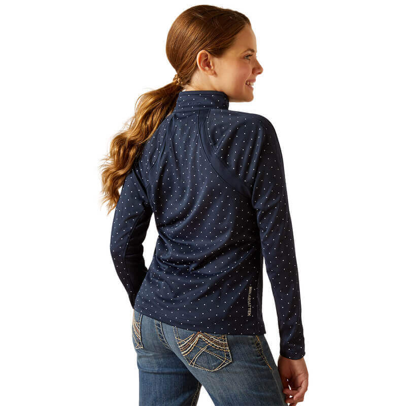 Girl with long ponytail in Ariat Youth Sunstopper 3.0 Navy Dot baselayer and blue jeans, back view.