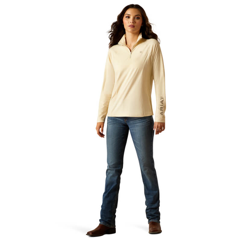 Woman in Ariat Laguna 2.0 ¼ Zip Top Summer Sand and jeans, facing forward in brown boots.
