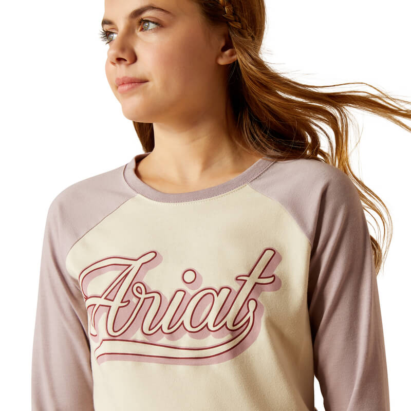 Young woman in an Ariat Youth Pony Script Baseball Long Sleeve Top in Natural.