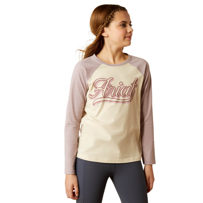 Young girl in an Ariat Youth Pony Script Baseball Long Sleeve Top Natural by Ariat.
