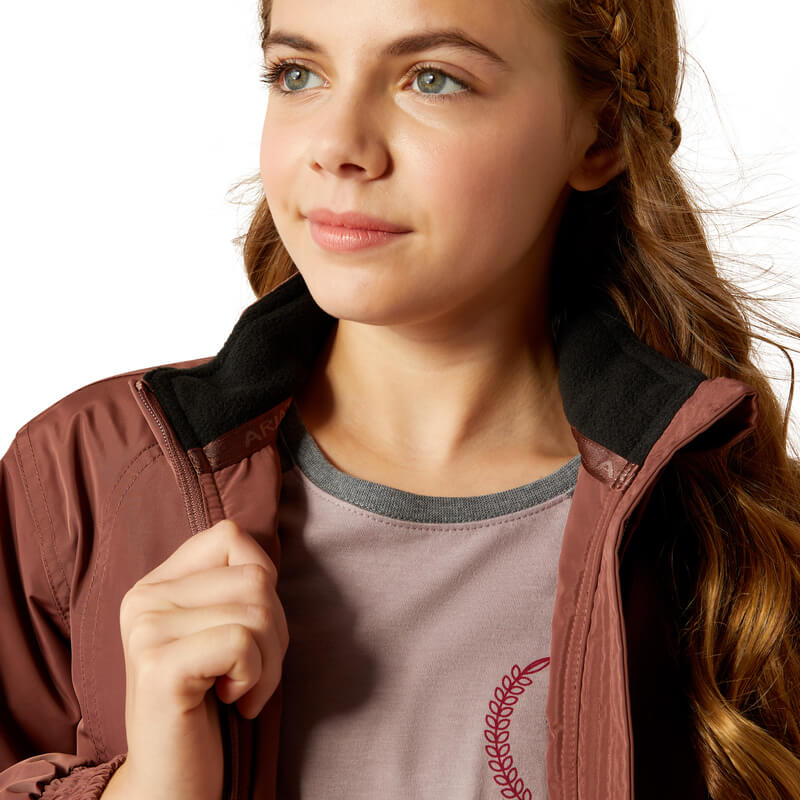 Girl in Ariat Youth Stable Jacket Marron and mauve shirt, looking aside.