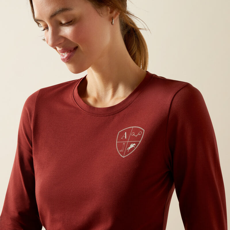 Smiling woman in Ariat Womens EQ Icons Long Sleeve T-Shirt in Madder Brown with chest emblem.