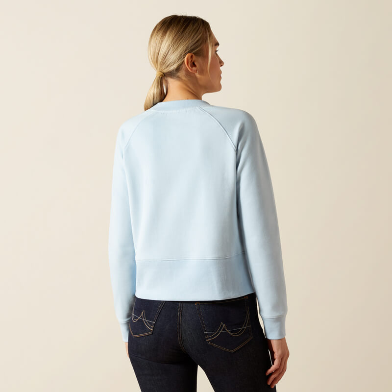 Woman in Ariat Womens Martine Sweatshirt Skyway and dark jeans, back facing the camera.