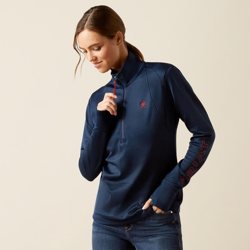 Woman in Ariat Womens Team EQ 1/2 Zip Pullover Navy by Ariat, looking down and smiling.